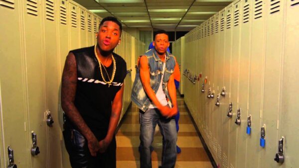 Two people pose in a school hallway filled with yellow lockers