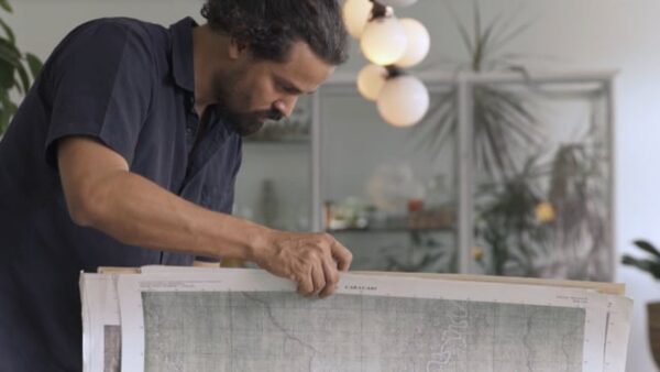 A man builds a wooden structure in a room with a modern pendant light behind him