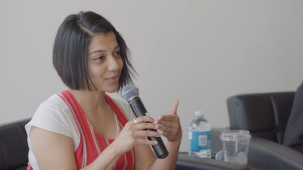 A female presenting person holds a microphone
