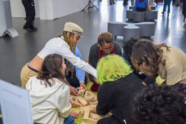 A group of people lean in together to view and discuss an object.