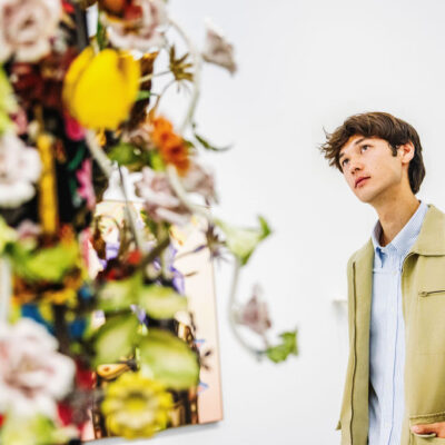 A young man looks up contemplatively at a colorful artwork that is out of focus.