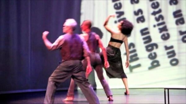 Low quality video still of three dancers performing on a stage.