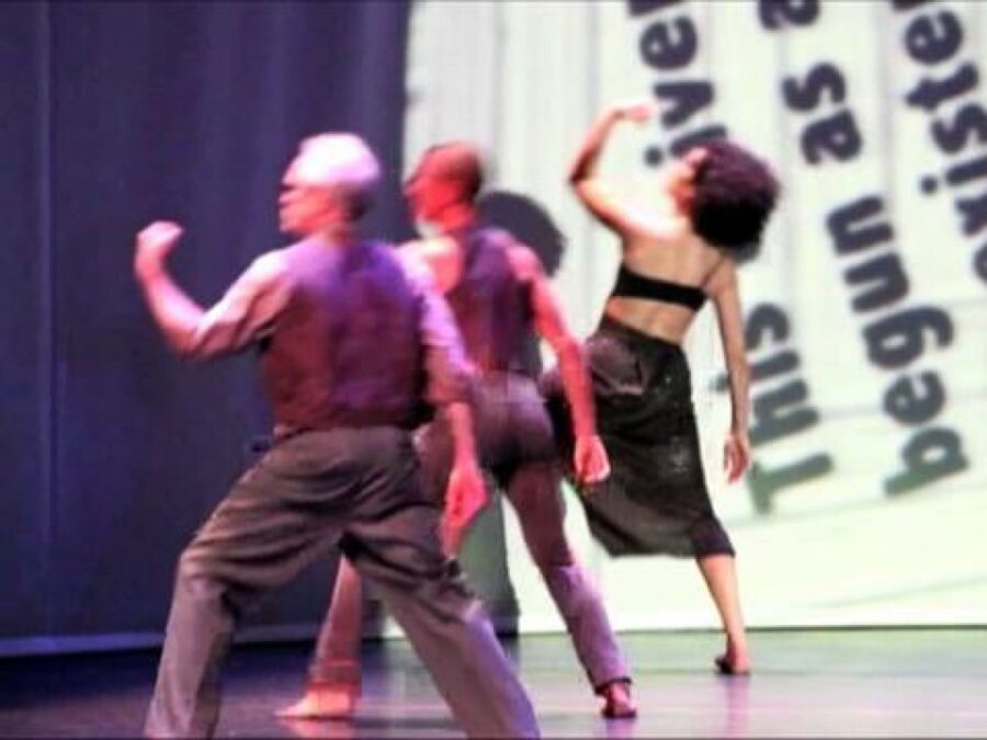 Low quality video still of three dancers performing on a stage.
