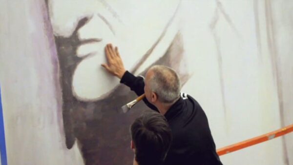 Two people face a wall with black paint on it