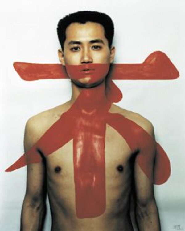 A photo of a shirtless man staring straight at the viewer with a red character over his body