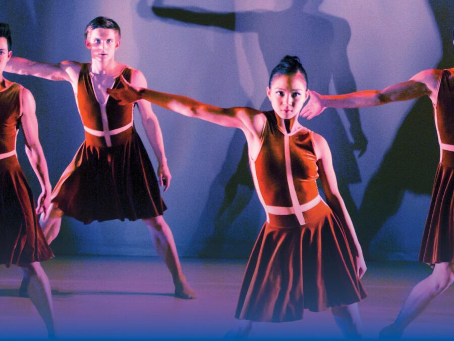 Four dancers in burnt orange dresses extend their right arm out to their sides