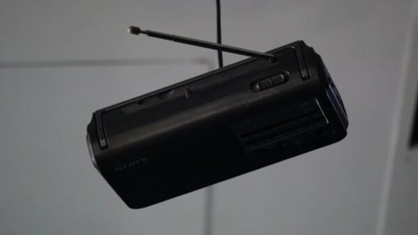 Close up of a black projector hanging from a ceiling in a darkened space