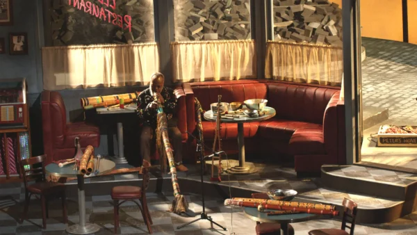 Interior of a diner filled with musical instruments. One person sits in a booth playing the didgeridoo