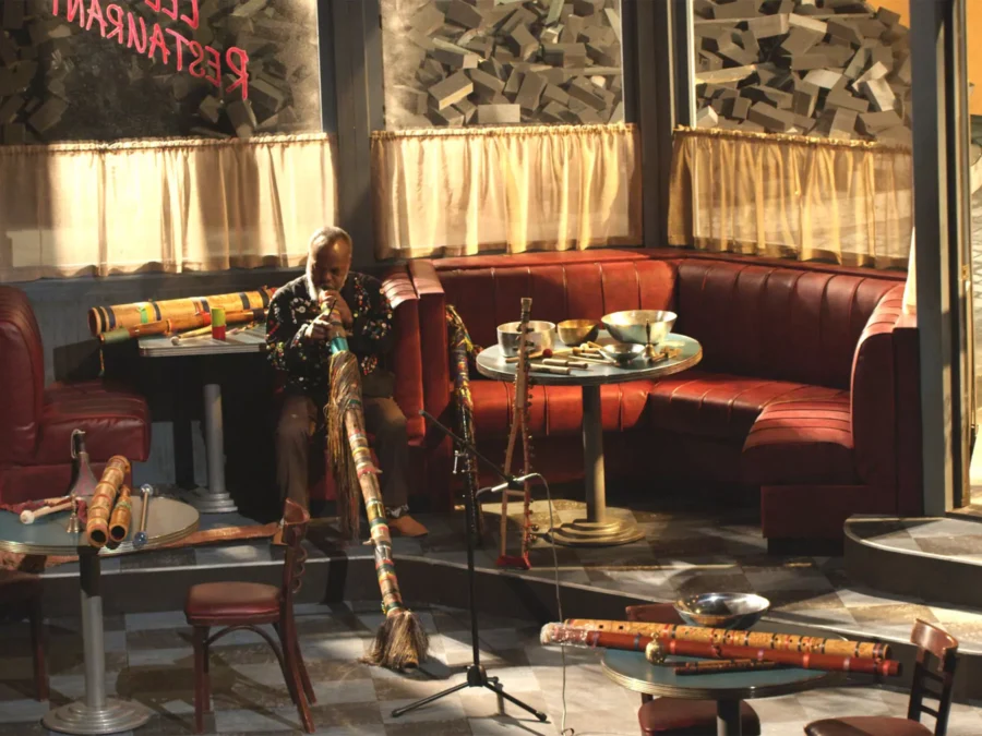 Interior of a diner filled with musical instruments. One person sits in a booth playing the didgeridoo