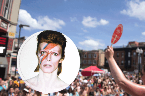 A cardboard fan with David Bowie as Aladdin Sane moves amongst various crowds