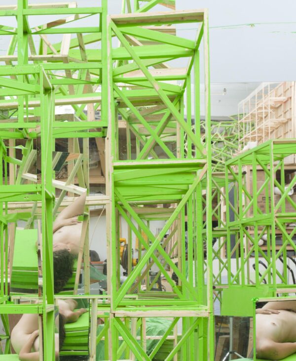 A lime green architectural support system with several nude bodies within it