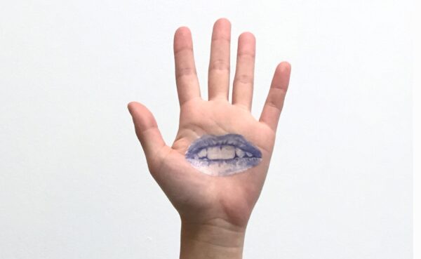 A left hand with a blue tattoo of lips on the open palm