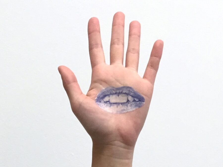 A left hand with a blue tattoo of lips on the open palm