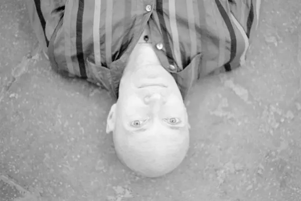 Black and white photo of a bald person from the shoulders up, viewed from upside down
