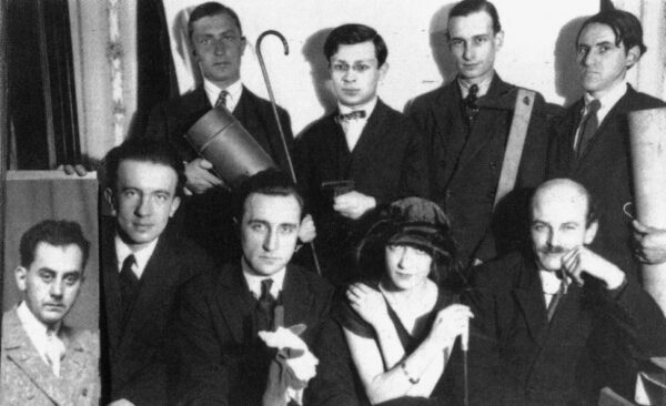A black and white photograph of well-dressed people with a portrait of someone inserted into the lower left-hand corner