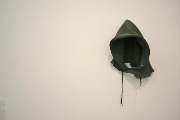 The hood from a green hoodie hanging on a white wall