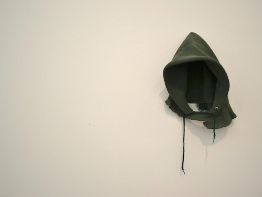 The hood from a green hoodie hanging on a white wall