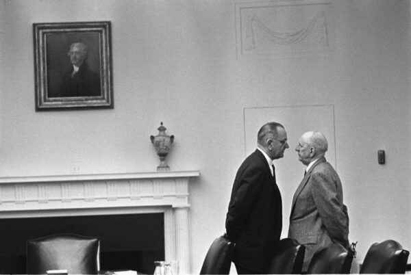 Black and white archival photo of President Johnson in the white house standing very close to another man in an intimidating pose.