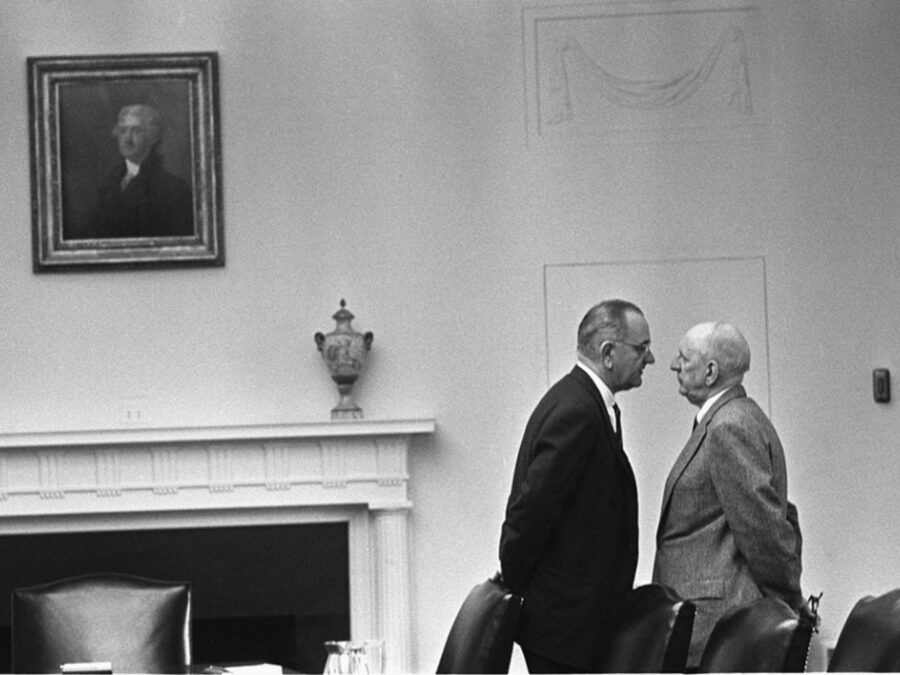 Black and white archival photo of President Johnson in the white house standing very close to another man in an intimidating pose.
