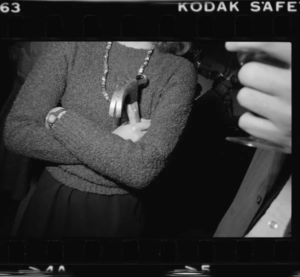 Torso view of a person holding a hammer close to their chest with their arms crossed