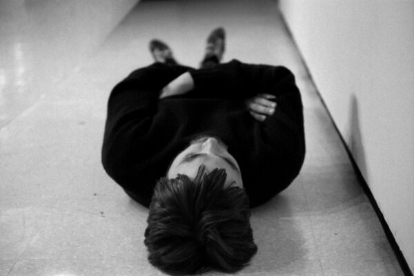 A person dressed in black lying on the ground as viewed from their head