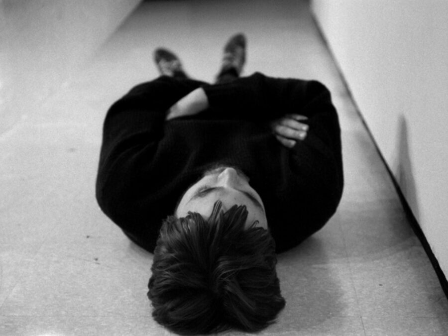 A person dressed in black lying on the ground as viewed from their head