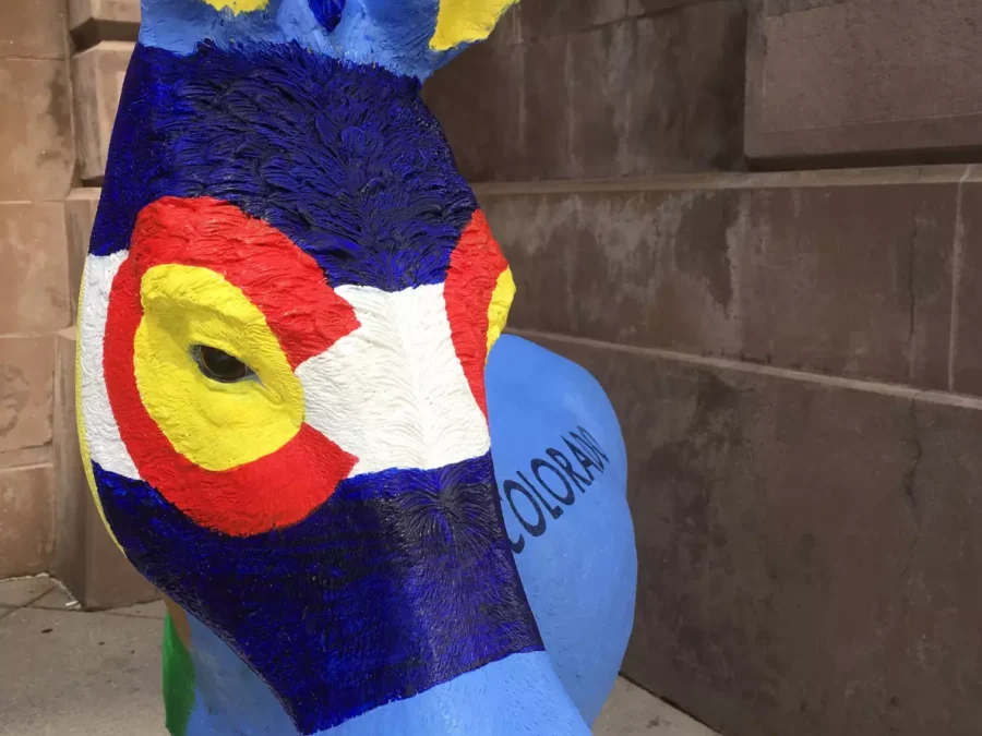 A blue donkey statue with its face painted in the style of the Colorado flag