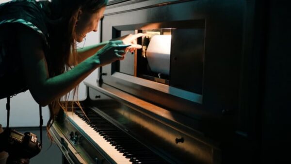 Closeup of a person working on the music sheet of a player piano