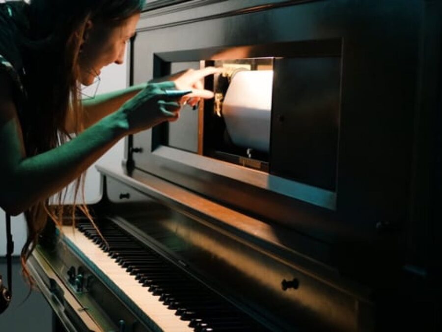 Closeup of a person working on the music sheet of a player piano