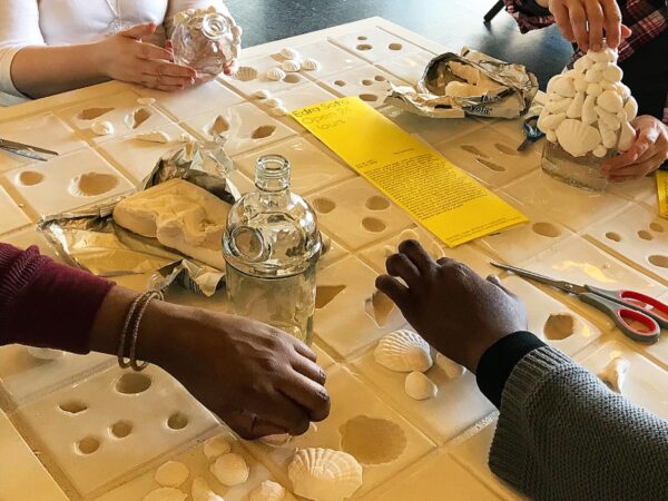 Close up of the hands of four people working on creating shells from yellow molds