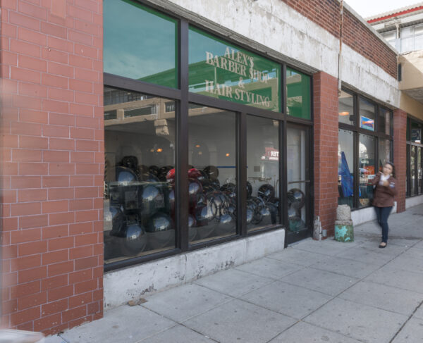 The exterior of a brick storefront with large windows and doors showing black balloons filling the space inside