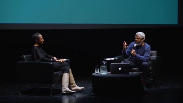 Two people sit across from each other on a stage