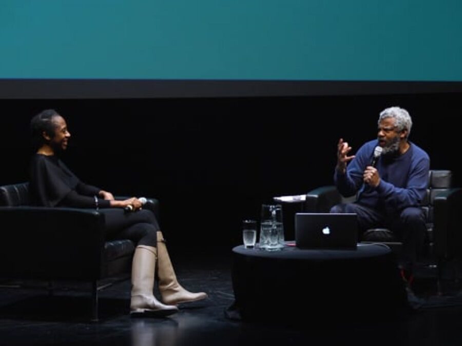 Two people sit across from each other on a stage