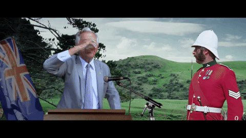 From behind a podium, Bob Hawke chugs a beer and tosses the empty cup forward as a red-suited guard looks on.