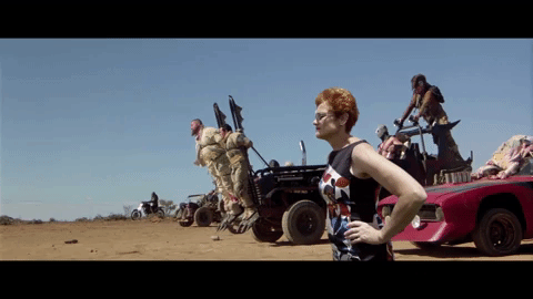 Pauline Hanson is inserted into a scene from Mad Max: Fury Road. She stands stoically, facing out to our left.
