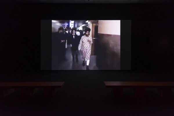 Grainy image of a group of people walking down a hall way in a pitch-black room