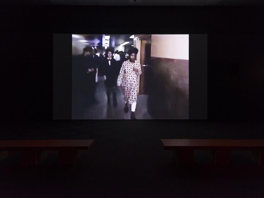 Grainy image of a group of people walking down a hall way in a pitch-black room