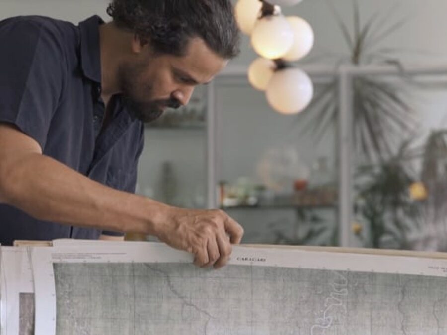 A man builds a wooden structure in a room with a modern pendant light behind him