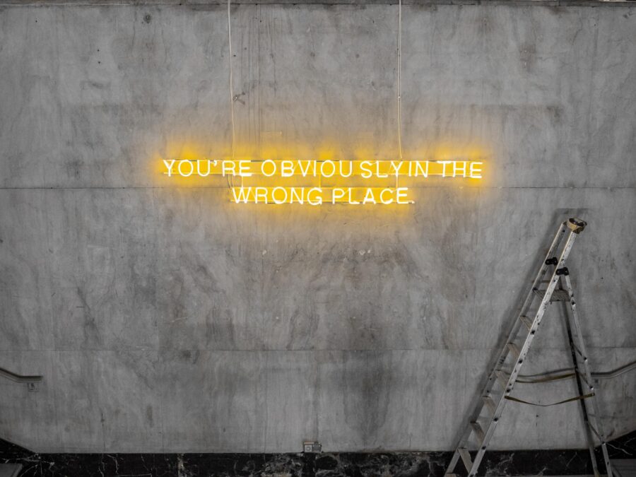A ladder next to a neon text reading You're obviously in the wrong place