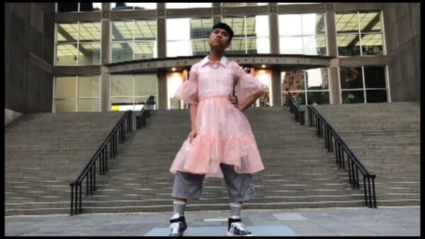 A person in a pink dress poses in front of the MCA