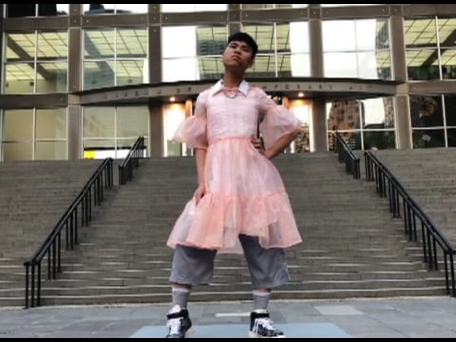 A person in a pink dress poses in front of the MCA