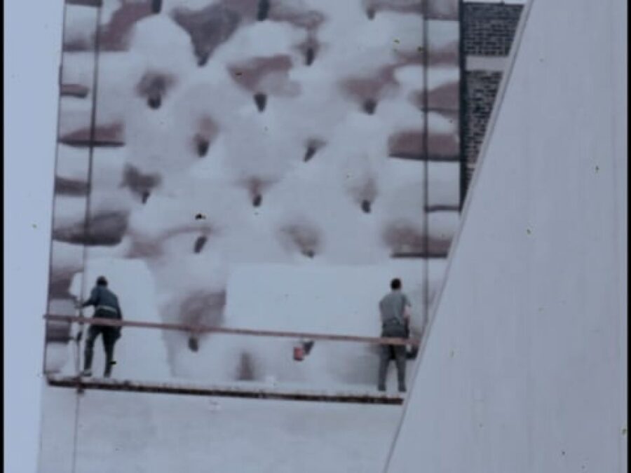 Two people stand on a makeshift swing stage scaffolding painting a giant pop-tart