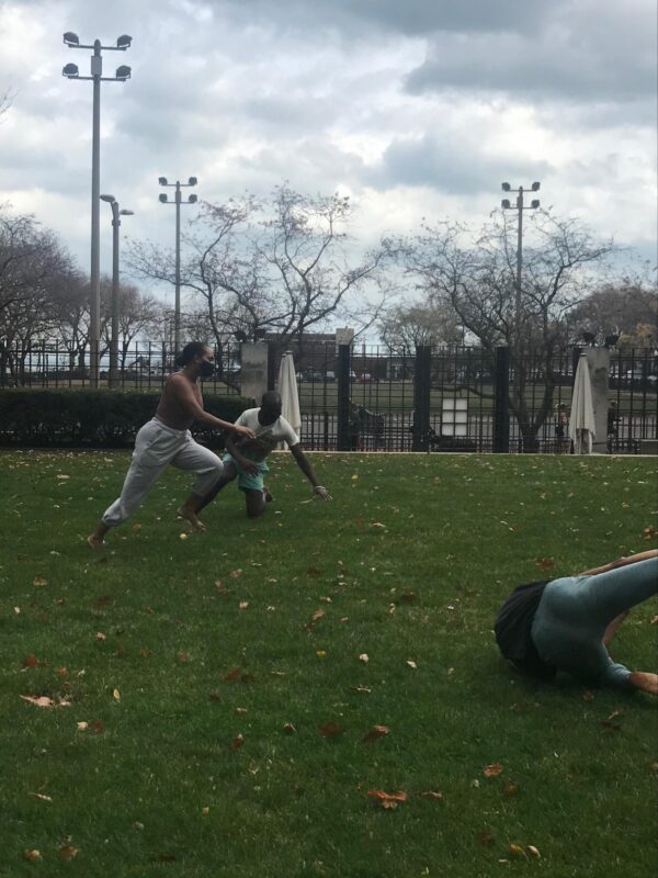 Three people tumbling in a park on a cloudy day