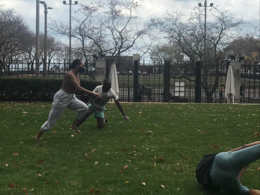 Three people tumbling in a park on a cloudy day