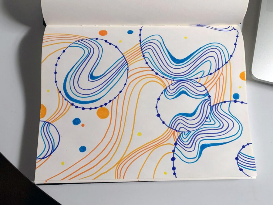 A blank notebook open to a drawing of circles and squiggly lines in blue and orange