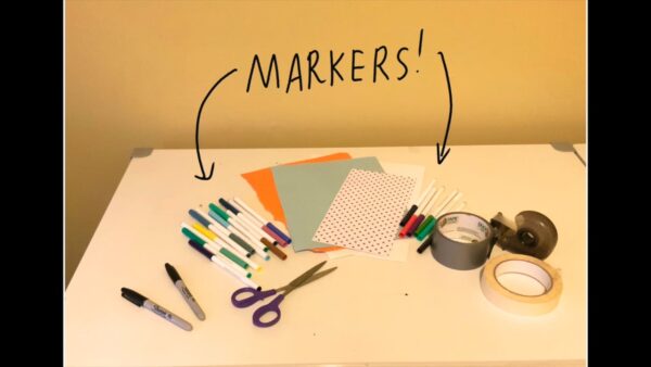 A table with art making materials on it and text with arrows pointing to Markers