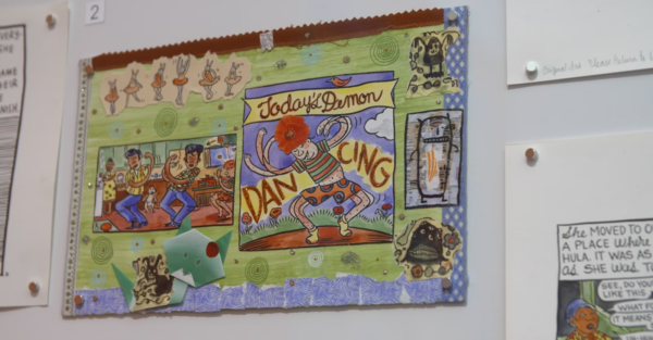 Close up of a drawing hanging on a white wall with other drawings pinned up just of camera