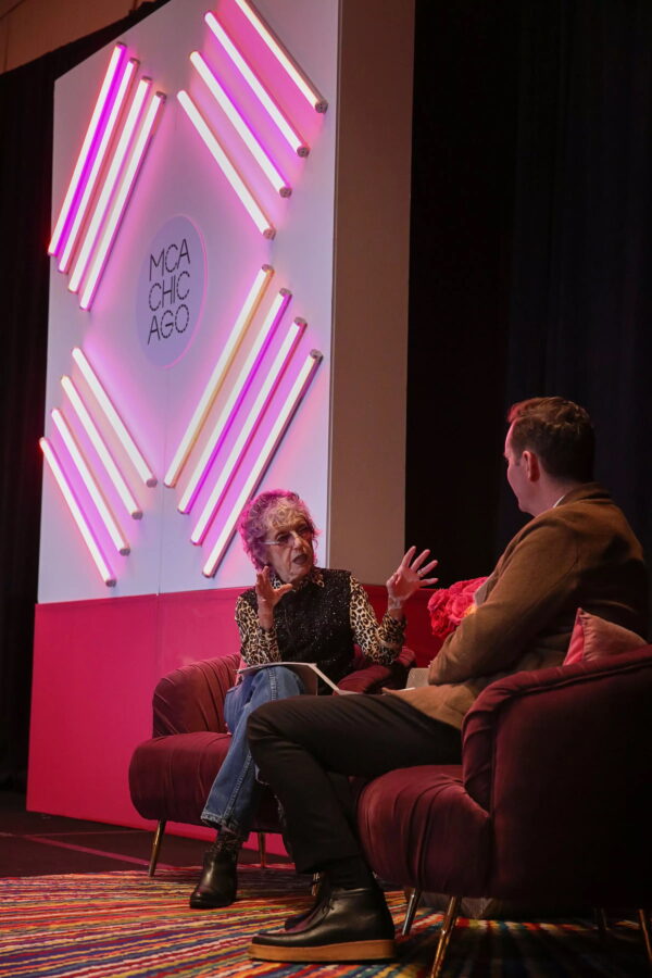 Two people sit on a red couch facing each other