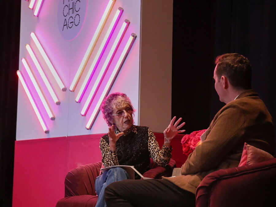 Two people sit on a red couch facing each other