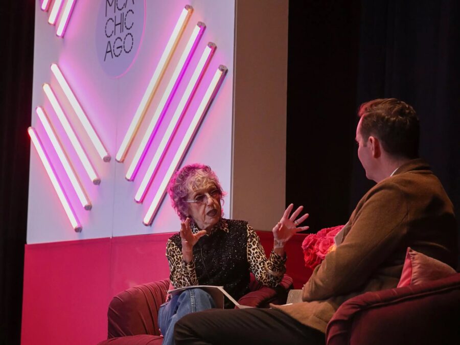 Two people sit on a red couch facing each other